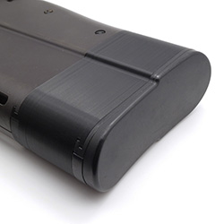 A single backplate charging handle lying against a white surface with part of the internal backplate structure visible.